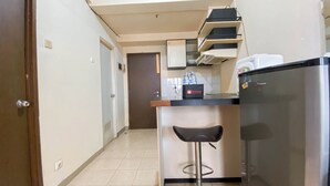 A compact kitchen with a refrigerator, a countertop, and a bar stool. - Nice 2Br At Apartment Suites @Metro (Bandung)