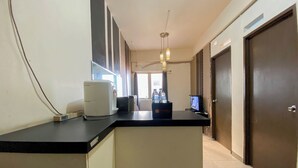 A hotel reception area with a counter, a coffee machine, a water cooler, and a television. - Nice 2Br At Apartment Suites @Metro (Bandung)