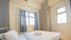 A hotel room with a bed, curtains, and a patterned wall. - Nice 2Br At Apartment Suites @Metro (Bandung)