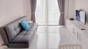 Ein modernes Wohnzimmer mit einem grauen Sofa, einem kleinen weißen Tisch und einem an der Wand befestigten Flachbildfernseher.