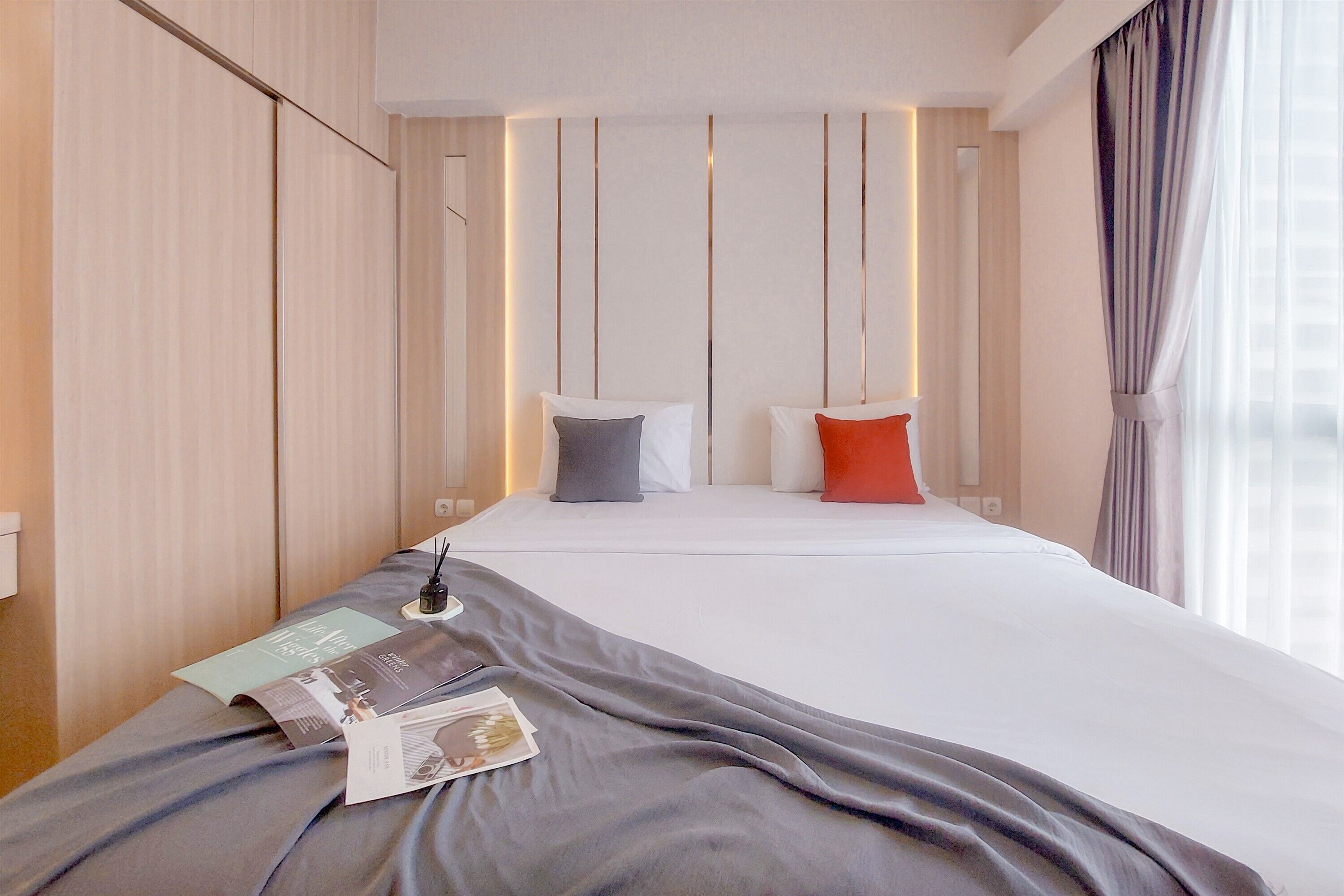 Une chambre d’hôtel avec un lit bien fait, une table de chevet avec une lampe et une fenêtre avec des rideaux.