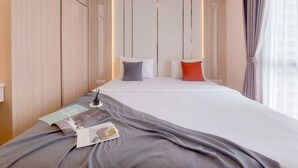 Ein Hotelzimmer mit einem ordentlich bezogenen Bett, einem Nachttisch mit Lampe und einem Fenster mit Vorhängen.