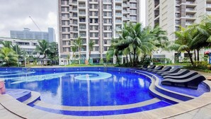 Une piscine à la forme en spirale, entourée de palmiers et avec un immeuble de grande hauteur en arrière-plan.