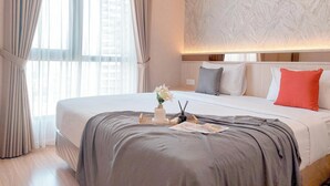 Une chambre d’hôtel moderne dotée d’un grand lit, d’un mur décoré d’un motif imitant le marbre et offrant une vue sur la ville grâce à de grandes fenêtres.