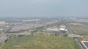 Luchtbeeld van een woongebied met meerdere flatgebouwen, een snelweg en een groot open veld.