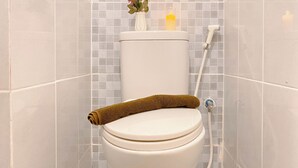 Eine Toilette mit einem braunen Handtuch, einer Vase mit Blumen und einer Kerze auf dem Tank.
