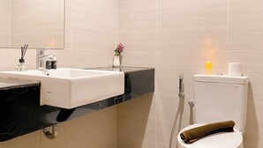 A modern bathroom with a white sink, black countertop, and a toilet with a towel. - Homey And Cozy Living Studio At West Vista Apartment (Jakarta)