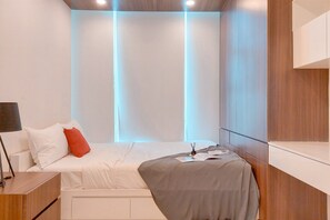 Cozy retreat with a neatly made bed and bedside table, featuring a lamp and vertical panelled walls.