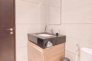 Bathroom features a large mirror, sink with single faucet, toilet, and showerhead.