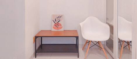 A small, modern room with a wooden table, a white chair, and a wall-mounted artwork.