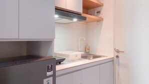 A modern kitchen with white cabinets, a stainless steel sink, and a black refrigerator. - Good Place Studio At Urbantown Serpong Apartment (South Tangerang)