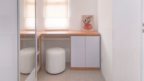 A room with a wooden desk, a white cabinet, and two white stools. - Good Place Studio At Urbantown Serpong Apartment (South Tangerang)