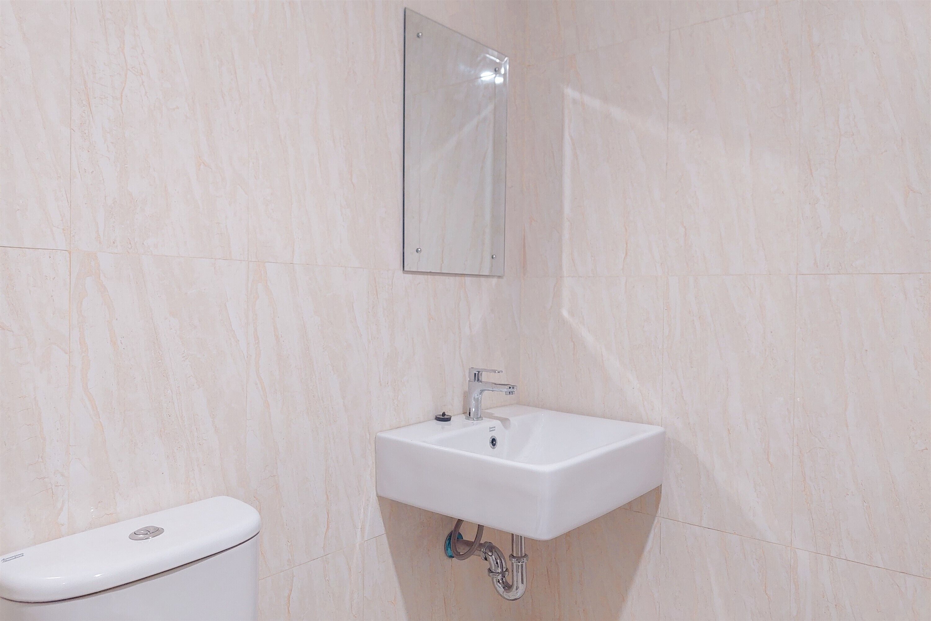Une salle de bain avec un lavabo blanc, un miroir et des toilettes.