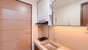 A bathroom with a wooden wardrobe, a white countertop, a built-in sink, and a mirror. - Comfort Studio Room At Vida View Apartment (Makassar)
