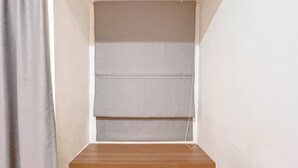 A corner of a room with a wooden shelf and a white wall. - Comfort Studio Room At Vida View Apartment (Makassar)
