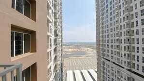 A high-rise building with multiple balconies and a view of a distant landscape. - Cozy Living 2Br Apartment At Tokyo Riverside Pik 2 (Teluknaga)