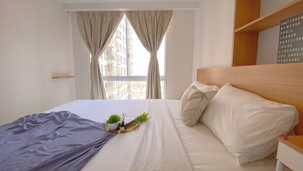 A neatly made bed with white linens, a grey throw blanket, and a small potted plant on a bedside table. - Cozy Living 2Br Apartment At Tokyo Riverside Pik 2 (Teluknaga)