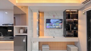 Une cuisine moderne équipée d’un téléviseur encastré, d’un réfrigérateur et d’un four à micro-ondes.
