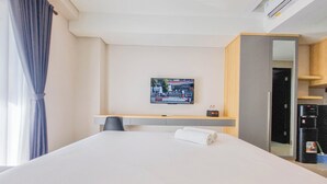 Ένα δωμάτιο ξενοδοχείου με ένα κρεβάτι, ένα γραφείο, μια καρέκλα, μια τηλεόραση τοποθετημένη στον τοίχο και ένα μίνι μπαρ.