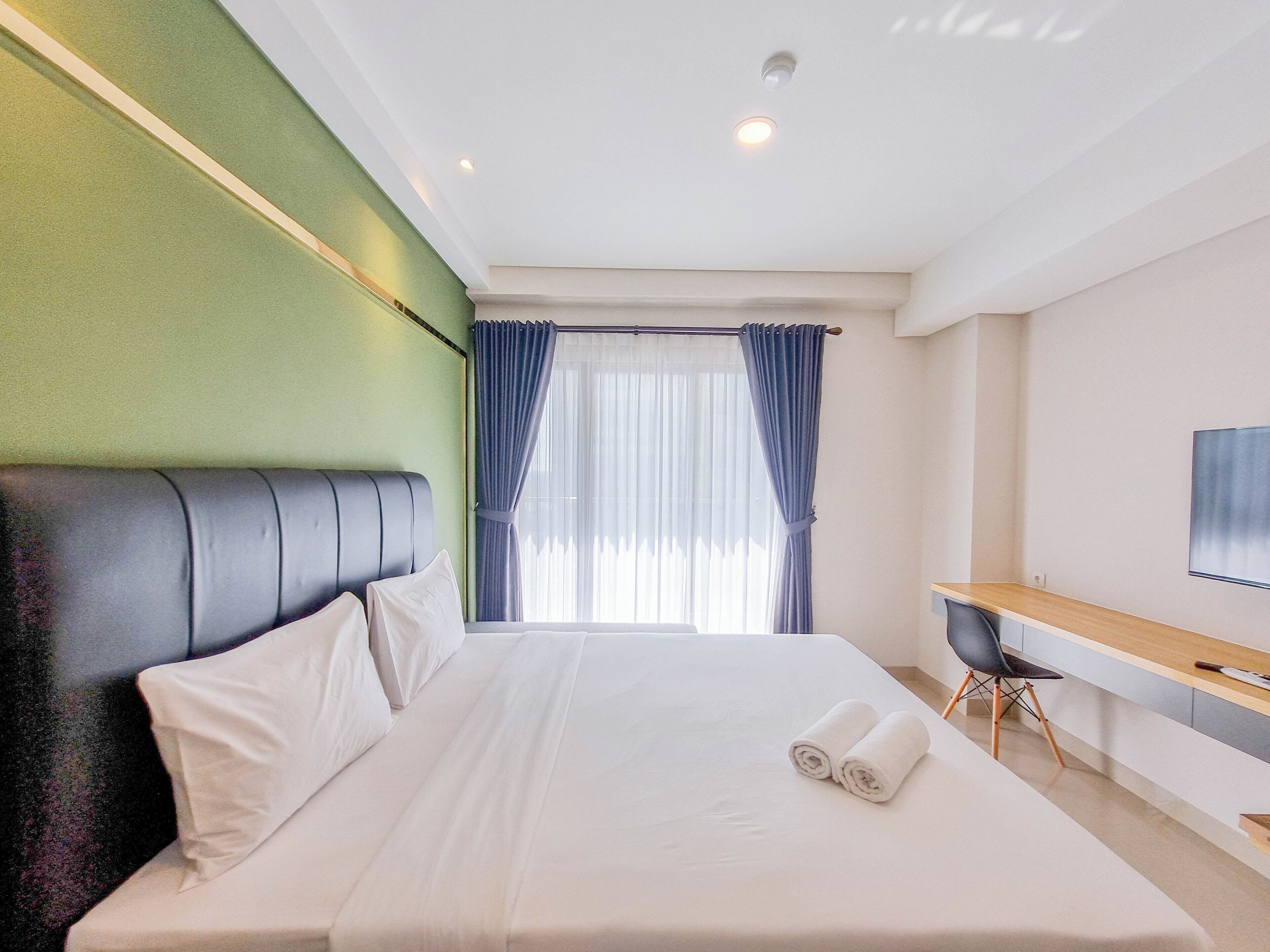A hotel room with a bed, a desk, and a TV.