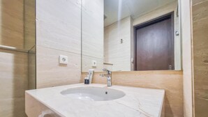 Ein Badezimmer mit Marmorwaschbecken, einem Spiegel und einer Tür.