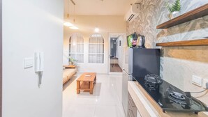 Eine moderne Küche mit einem schwarzen Herd, einem Holztisch und einem eingebauten Backofen. Weiße Arbeitsplatte und Rückwand mit einem Steinmuster.