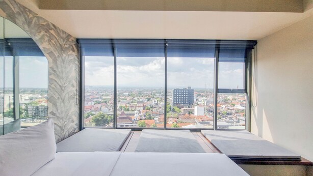 Ein modernes Hotelzimmer mit großem Fenster und Blick auf die Stadt.