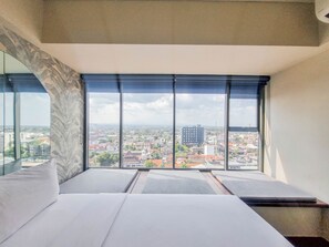 A modern hotel room with a large window offering a city view. - Good Place And Homey 1Br At Uttara The Icon Apartment (Depok)