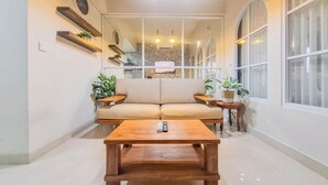 Ein modernes Wohnzimmer mit einer Couch, einem Holztisch und zwei Beistelltischen mit Pflanzen.