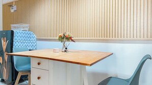 A room with a wooden desk, a chair, a small table, and a wall-mounted air purifier.