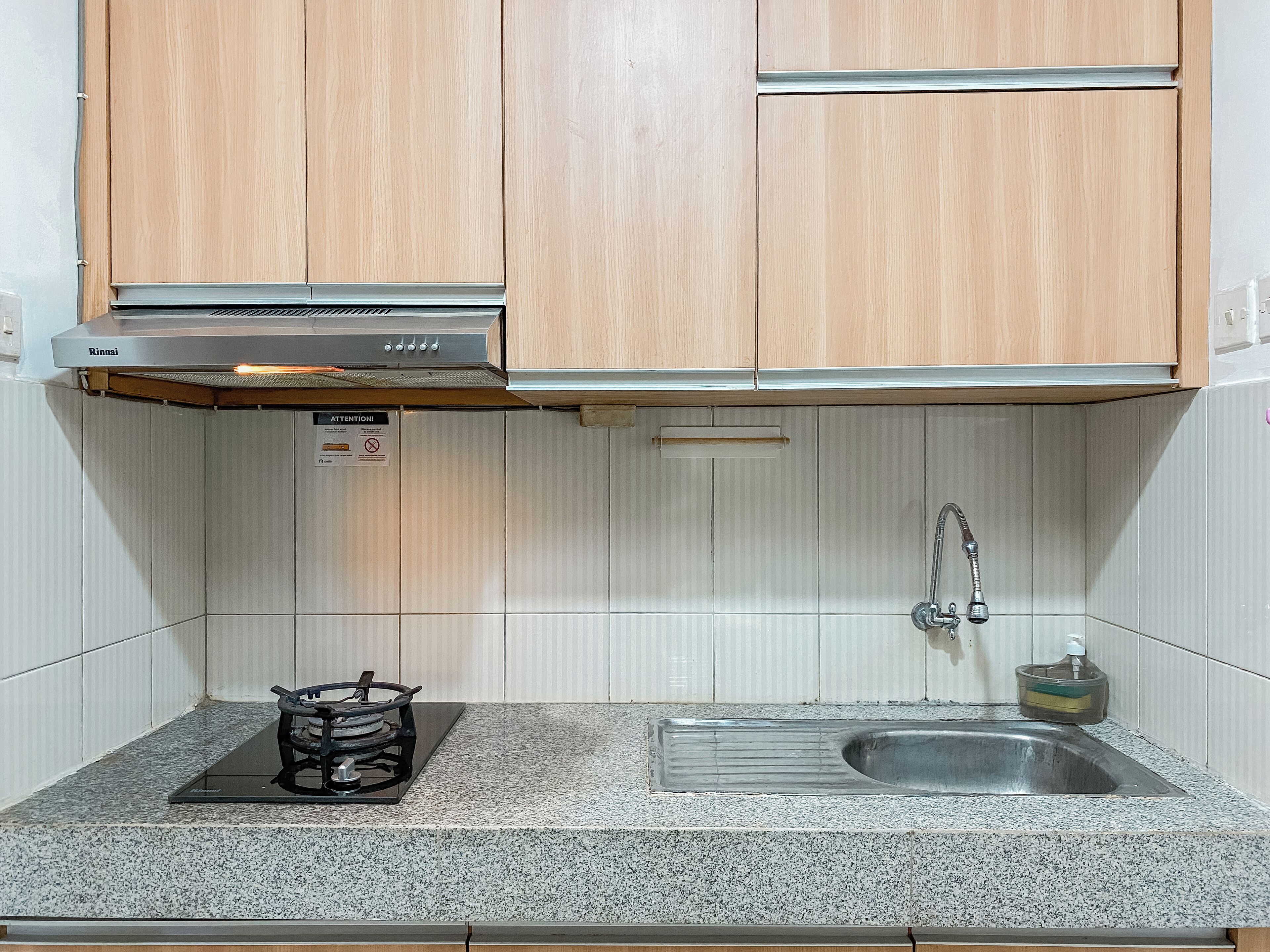 A kitchen with wooden cabinets, a stainless steel sink, and a gas stove.