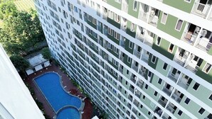 A high-rise building with multiple balconies and a central swimming pool.