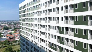A multi-story building with balconies and windows, surrounded by a residential area.