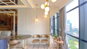 Une chambre moderne avec un coin repas, deux chaises, une table et une vue sur la ville.