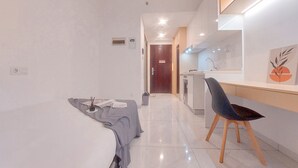 Ein modernes Hotelzimmer mit Bett, Schreibtisch mit Stuhl, Badezimmer und Küchenzeile.
