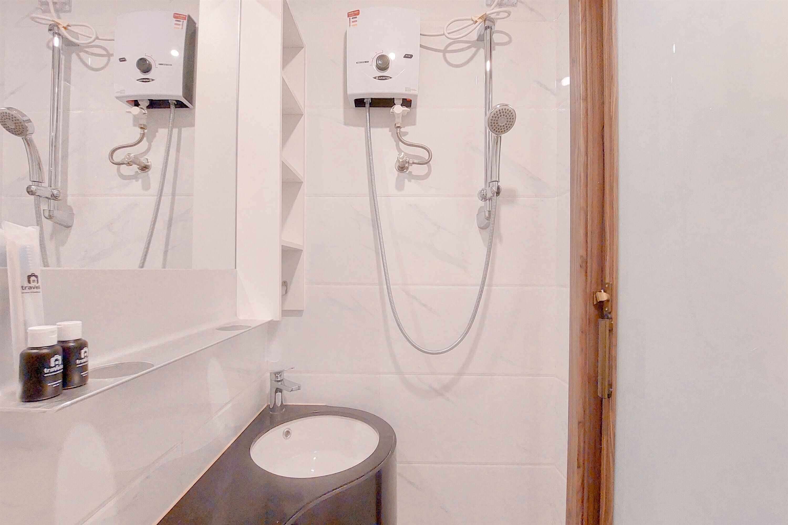 Une salle de bain avec un lavabo blanc, un miroir et deux pommes de douche fixées au mur.