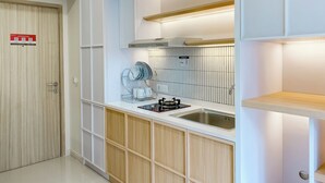 A modern kitchen with white cabinetry, a stainless steel sink, and a built-in stove. - Well Furnished And Comfort 2Br Meikarta Apartment (Cikarang)