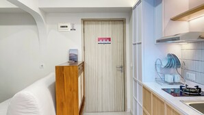 A compact kitchen with a built-in stove, a dish rack, and a wooden cabinet. - Well Furnished And Comfort 2Br Meikarta Apartment (Cikarang)