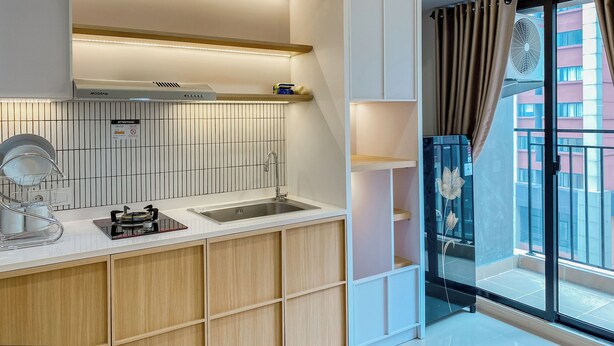 A modern kitchen with a built-in stove, sink, and overhead ventilation. - Well Furnished And Comfort 2Br Meikarta Apartment (Cikarang)