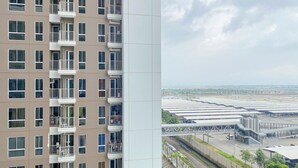 En flereetagers boligbygning med altaner og udsigt over en parkeringsplads med flere bygninger.