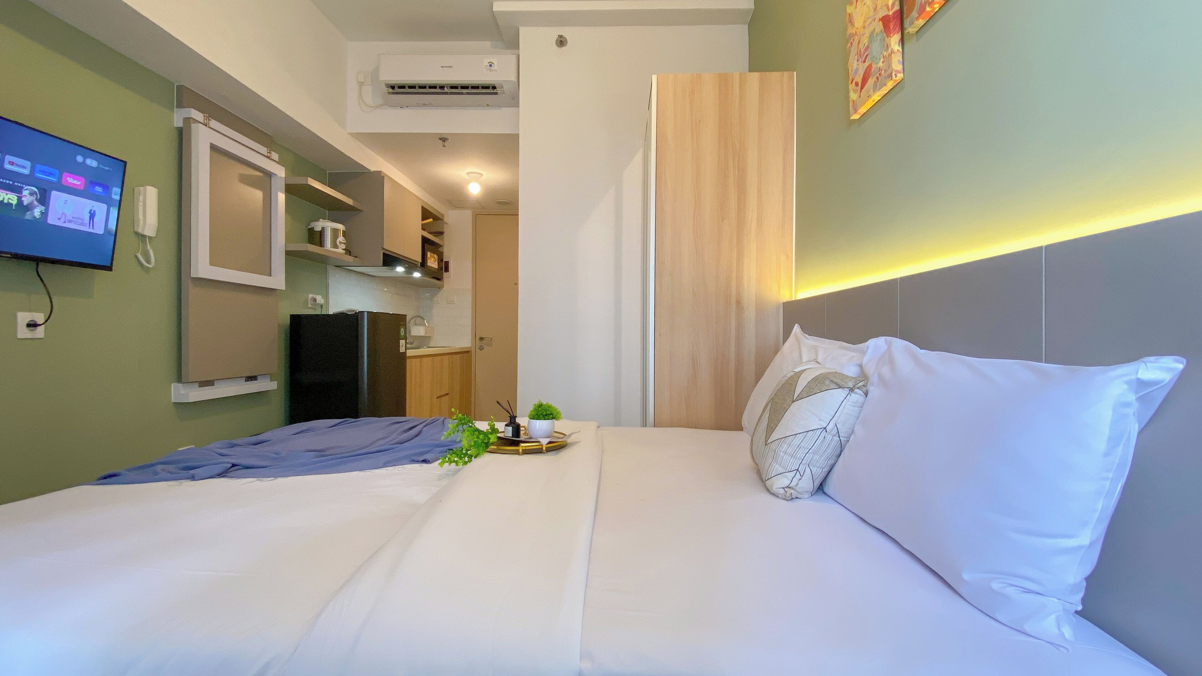 Een hotelkamer met een bed, een televisie, een kitchenette en een badkamer.