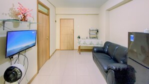 Een woonkamer met een televisie, een bank, een plafondventilator en een deur.