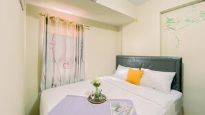 Hotelkamer met een bed, raam met gordijnen, airconditioning en een bloementapijt aan de muur.