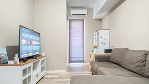 Un salon équipé d’un téléviseur, d’un canapé, d’un meuble et d’un réfrigérateur.