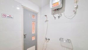 Une salle de bain équipée d’une douche, d’un sèche-mains et d’un panneau indiquant qu’il est interdit de fumer.