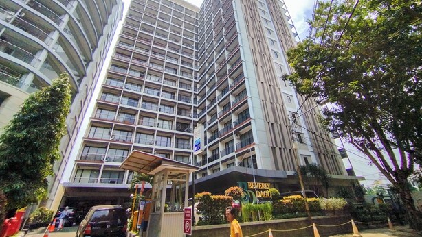 Un hôtel à plusieurs étages, doté d’un design moderne, avec une entrée imposante, un espace abrité et un panneau indiquant l’emplacement du parking.