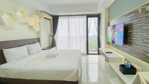 Une chambre d’hôtel moderne avec un grand lit, un téléviseur fixé au mur et un balcon agrémenté de rideaux.