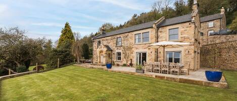 A stone house with a well-maintained lawn and outdoor seating area.