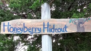 Un segnale direzionale in legno con la scritta 'HoneyBerry Hideout'.