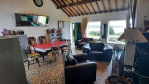 A cozy living room with a red table, leather sofa, and a large window offering a view of the outdoors. - Unique beachfront cottage at Fintra Bay Donegal (Killybegs)